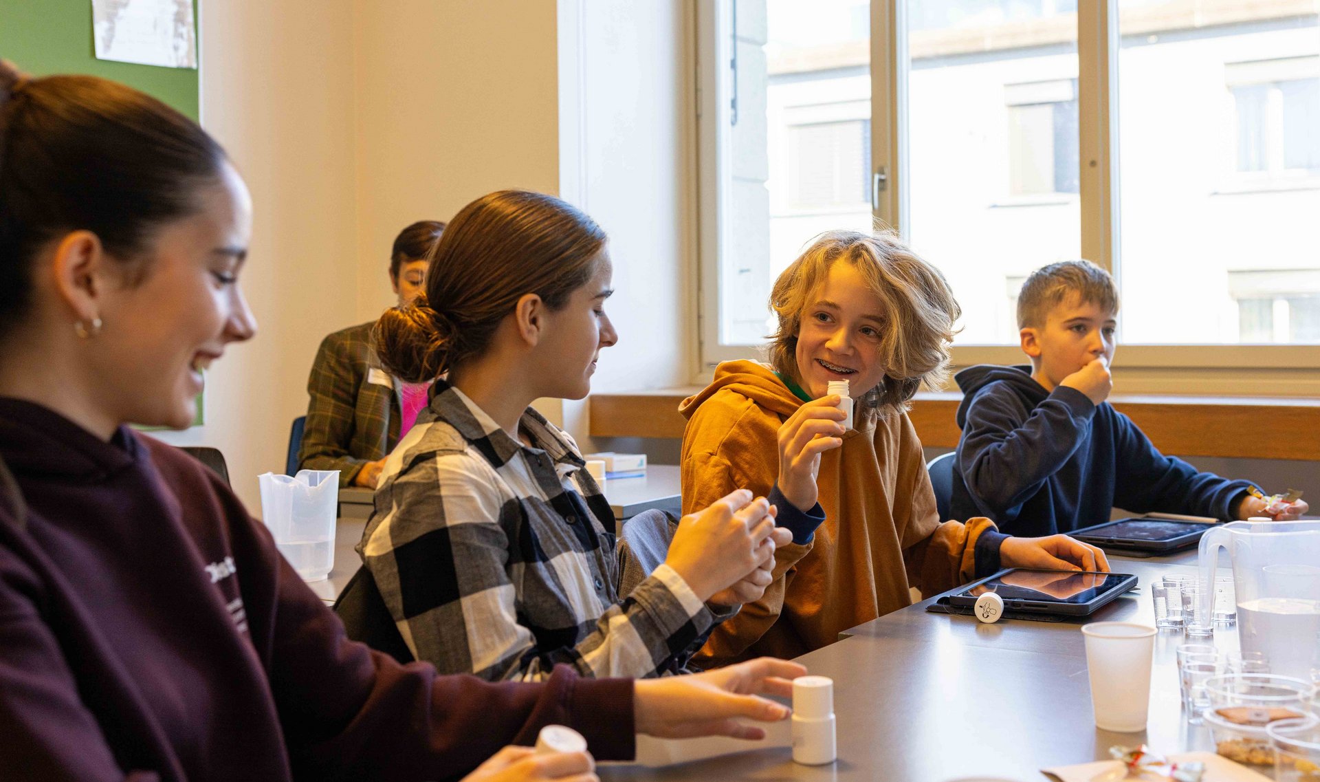 Des élèves expérimentent dans une salle de classe lors du TecDay et rient.